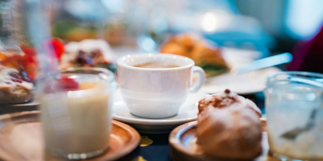 A breakfast table with a cup of coffee, pastries and milk