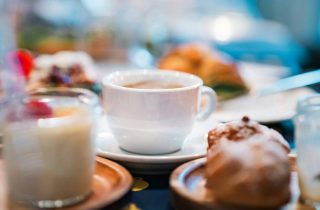 A breakfast table with a cup of coffee, pastries and milk