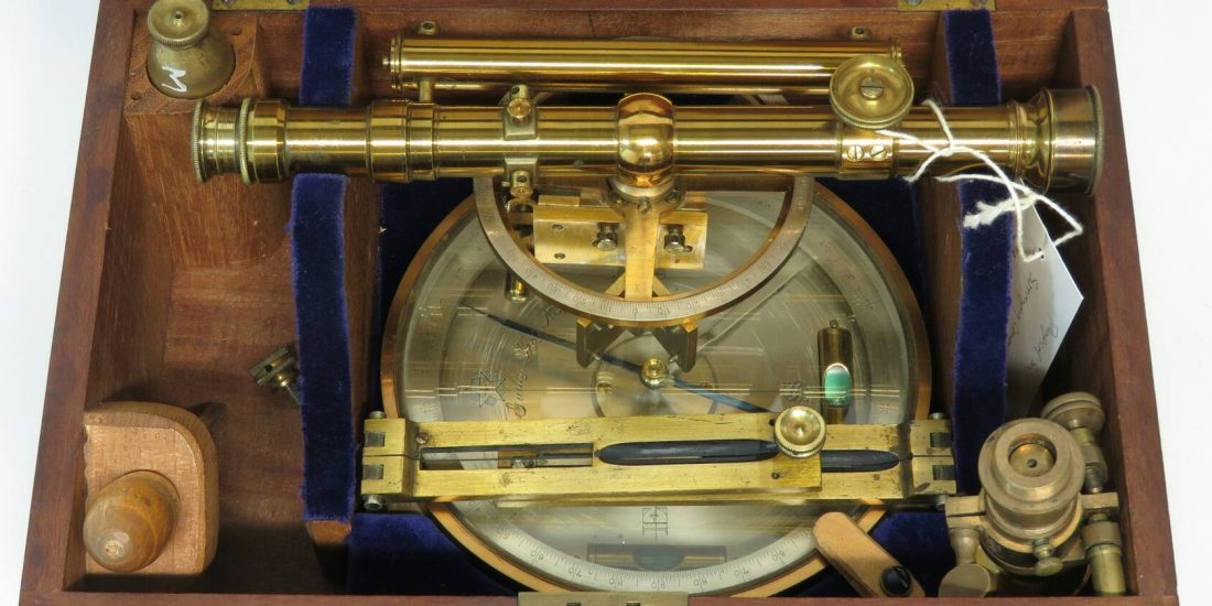 An antique brass surveying instrument in its fitted wooden case