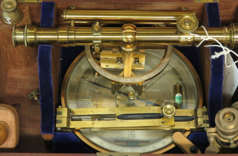 An antique brass surveying instrument in its fitted wooden case