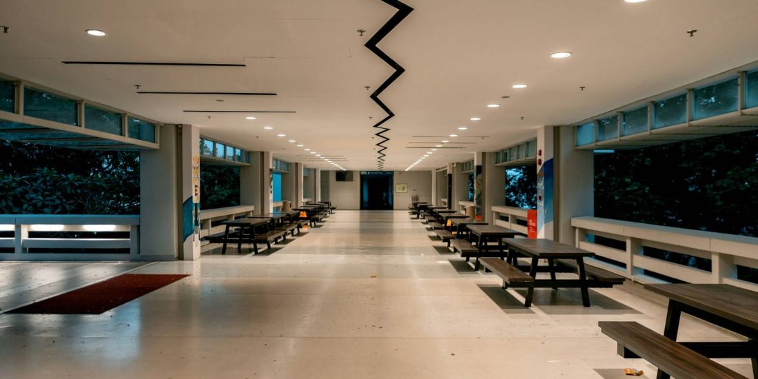 An empty school canteen with rows of benches and tables