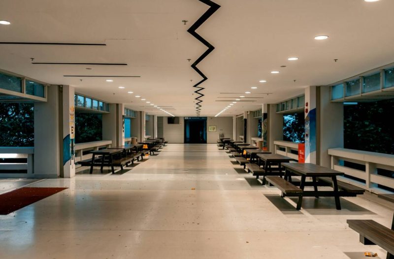 An empty school canteen with rows of benches and tables