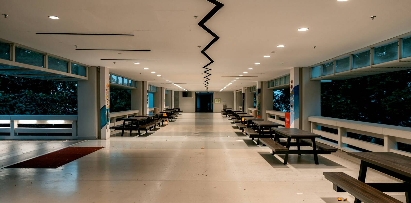 An empty school canteen with rows of benches and tables