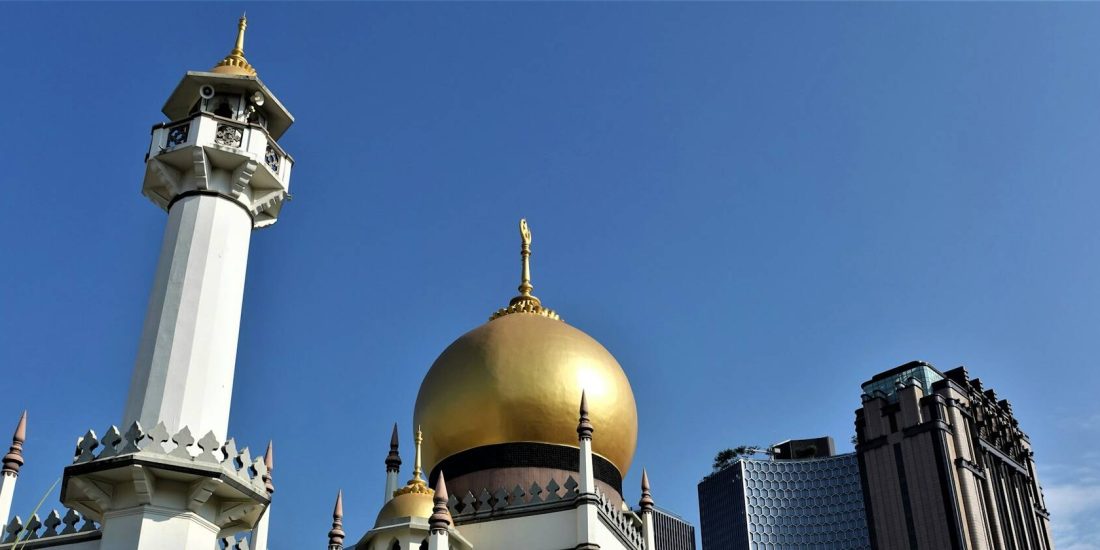 The minaret and golden dome of Sultan Mosque against a blue sky