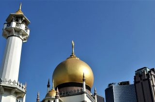 The minaret and golden dome of Sultan Mosque against a blue sky